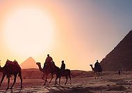 Pyramiden und ägyptische Kamele im Sonnenuntergang